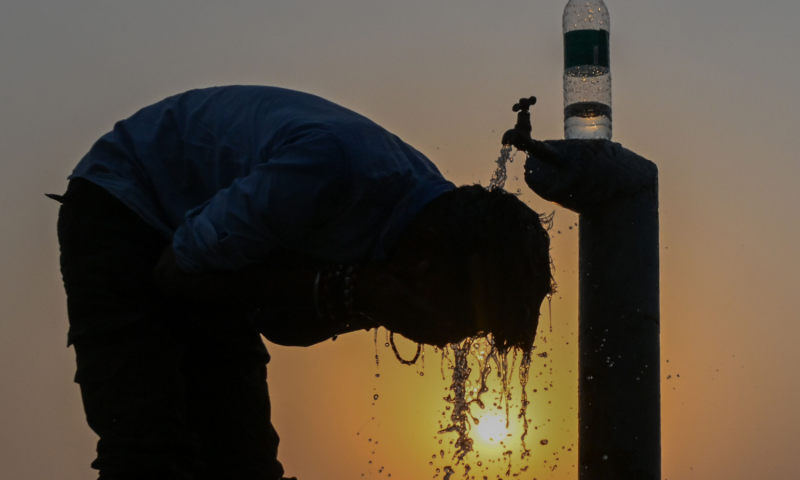 Person, die sich in der Hitze an einem Wasserspender erfrischt